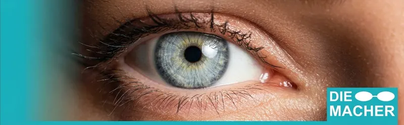 Nahaufnahme eines blaugrauen Auges mit dem Logo der Brillenmacher