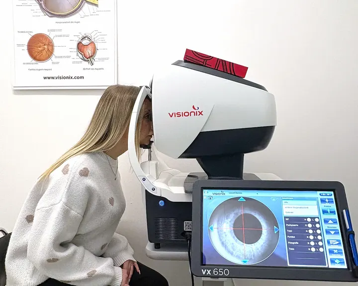 Kundin schaut in den Visionix VX 650, daneben der Bildschirm mit der Aufnahme ihres Auges